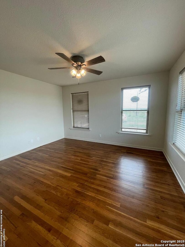 spare room featuring a ceiling fan, dark wood-style floors, and a textured ceiling