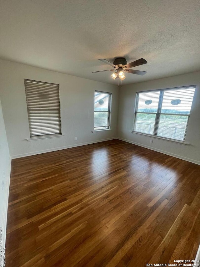 spare room featuring dark wood-style floors, baseboards, a textured ceiling, and ceiling fan