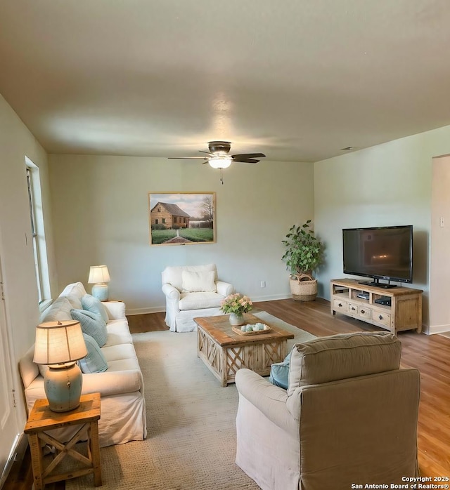 living area featuring a ceiling fan, wood finished floors, and baseboards