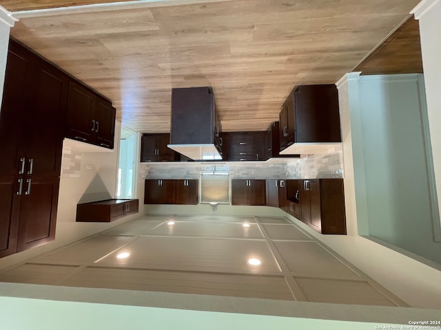 kitchen featuring backsplash, exhaust hood, dark brown cabinetry, and wooden ceiling