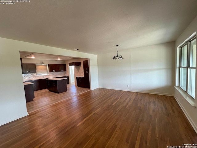 unfurnished living room with dark wood finished floors, baseboards, and a textured ceiling