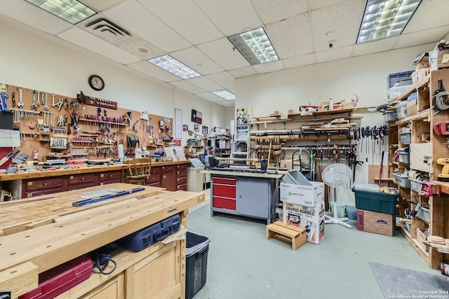 miscellaneous room with a paneled ceiling, concrete flooring, and a workshop area