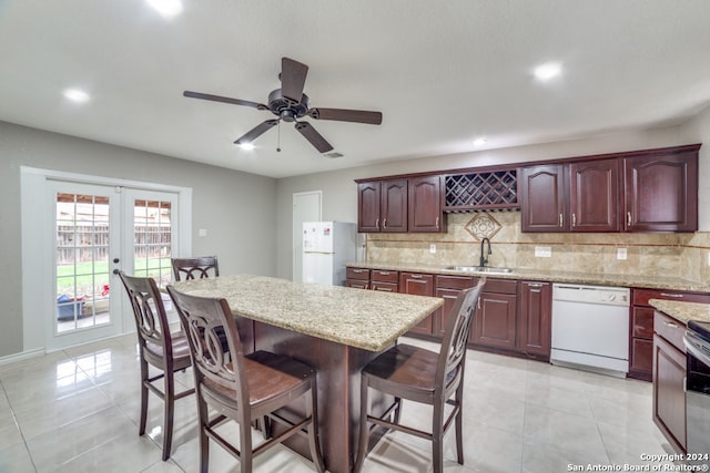 kitchen with light tile patterned flooring, light stone countertops, white appliances, and sink