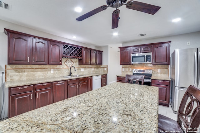 kitchen featuring light tile patterned flooring, ceiling fan, stainless steel appliances, decorative backsplash, and sink