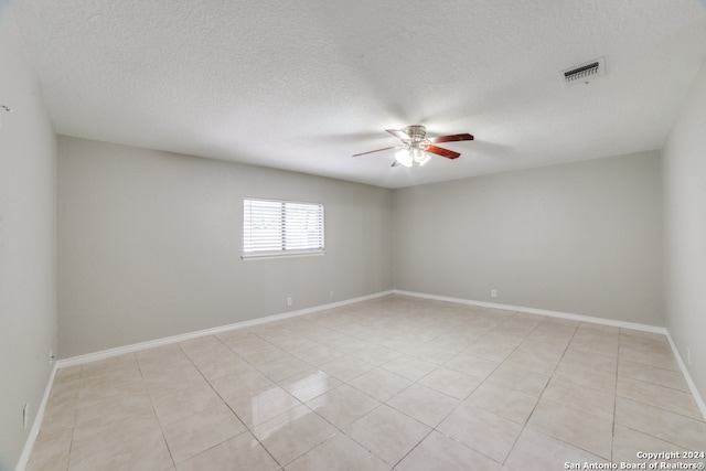 tiled empty room featuring a textured ceiling and ceiling fan