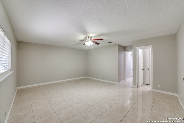 tiled spare room with a textured ceiling and ceiling fan