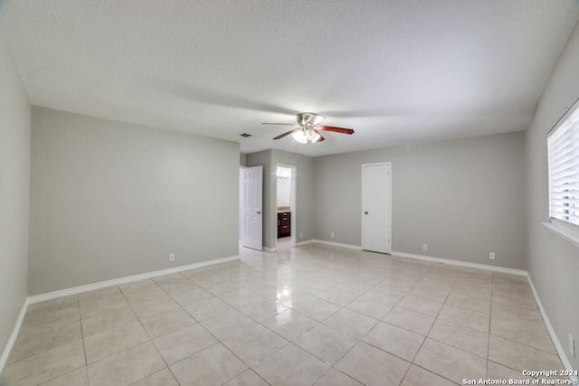 tiled spare room featuring a textured ceiling and ceiling fan