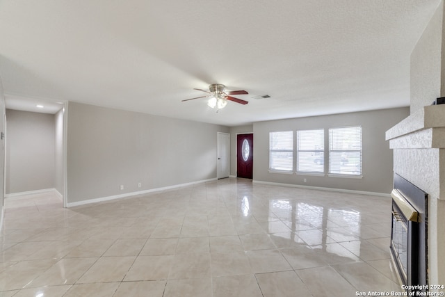 unfurnished living room featuring light tile patterned floors, a tiled fireplace, and ceiling fan