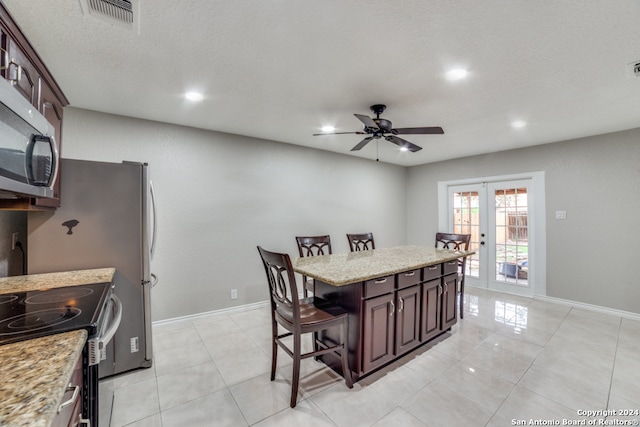 tiled dining space featuring a textured ceiling, french doors, and ceiling fan