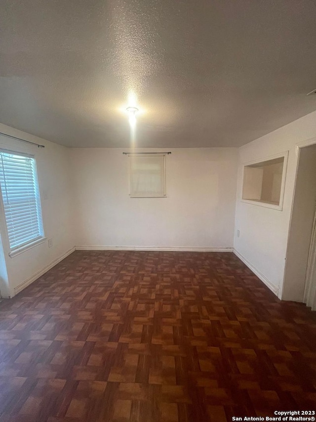 unfurnished room with dark parquet floors and a textured ceiling