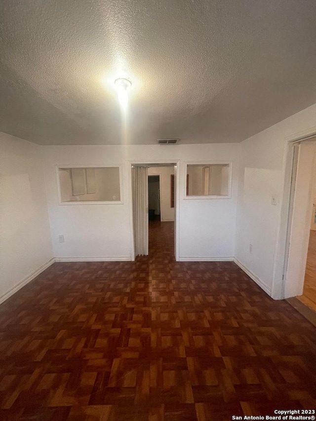 empty room featuring a textured ceiling and dark parquet floors