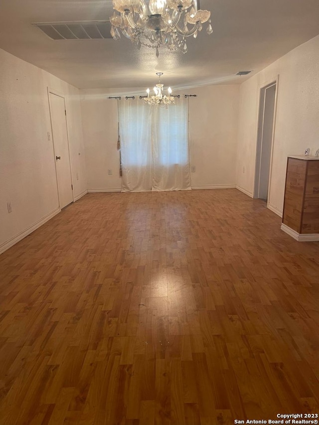 empty room with an inviting chandelier and hardwood / wood-style flooring