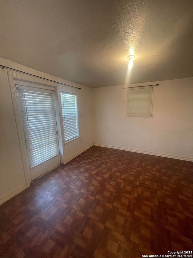 unfurnished room with dark parquet floors and a textured ceiling