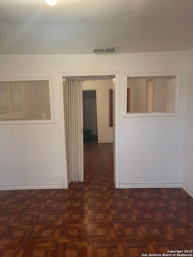 spare room with dark parquet flooring and a textured ceiling