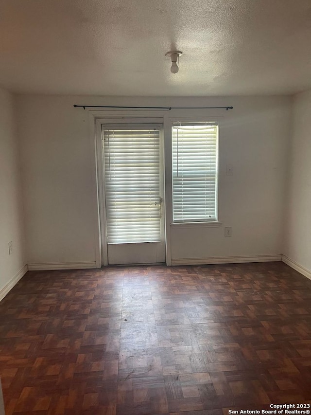 empty room featuring dark parquet flooring and a textured ceiling