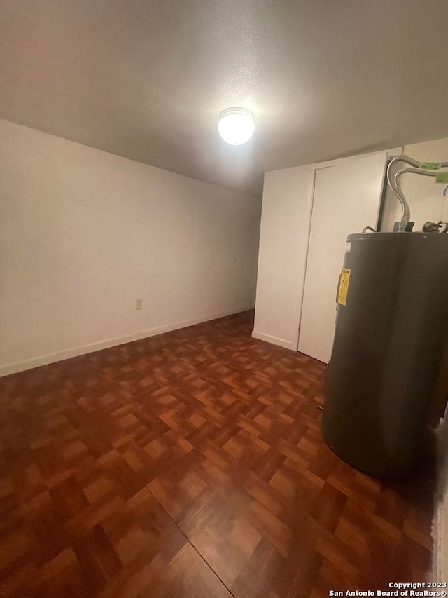 basement with water heater, dark parquet flooring, and a textured ceiling