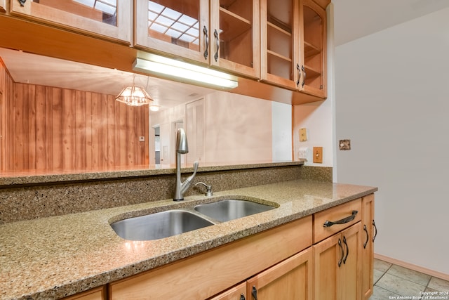 kitchen featuring sink, light tile patterned flooring, light stone countertops, and pendant lighting