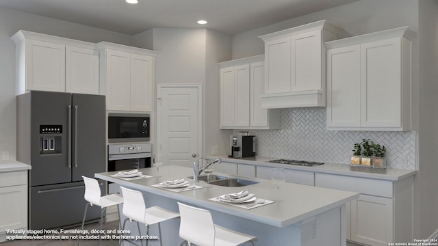 kitchen with sink, a breakfast bar area, stainless steel appliances, decorative backsplash, and white cabinets