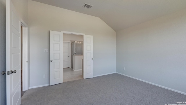 unfurnished bedroom featuring light colored carpet and vaulted ceiling