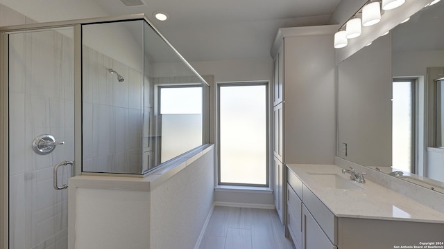 bathroom with vanity, an enclosed shower, and a wealth of natural light