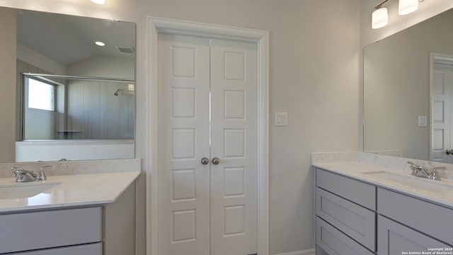 bathroom with tiled shower and vanity