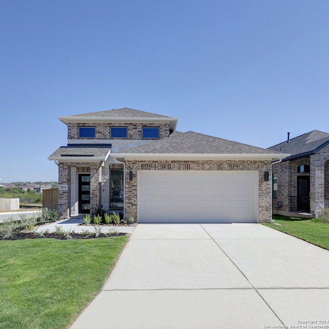 prairie-style house featuring a garage and a front yard