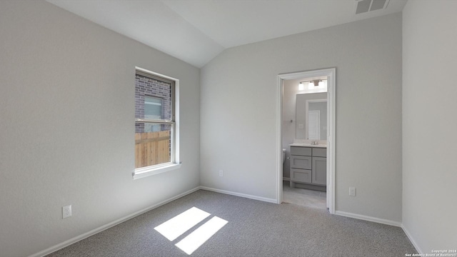 unfurnished bedroom featuring connected bathroom, vaulted ceiling, and light colored carpet