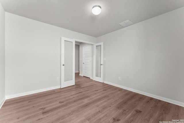 unfurnished bedroom featuring french doors and light hardwood / wood-style flooring