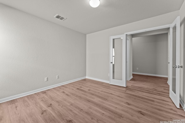 unfurnished bedroom with a closet, light hardwood / wood-style flooring, and french doors