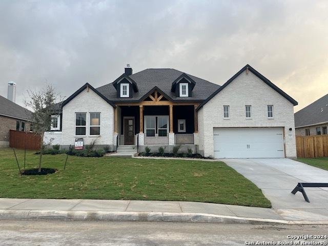 view of front of house with a porch, fence, a garage, driveway, and a front lawn