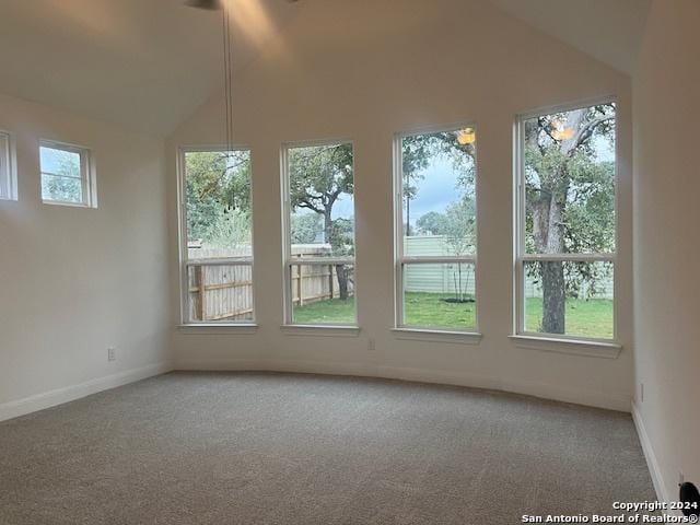 carpeted empty room featuring lofted ceiling and plenty of natural light