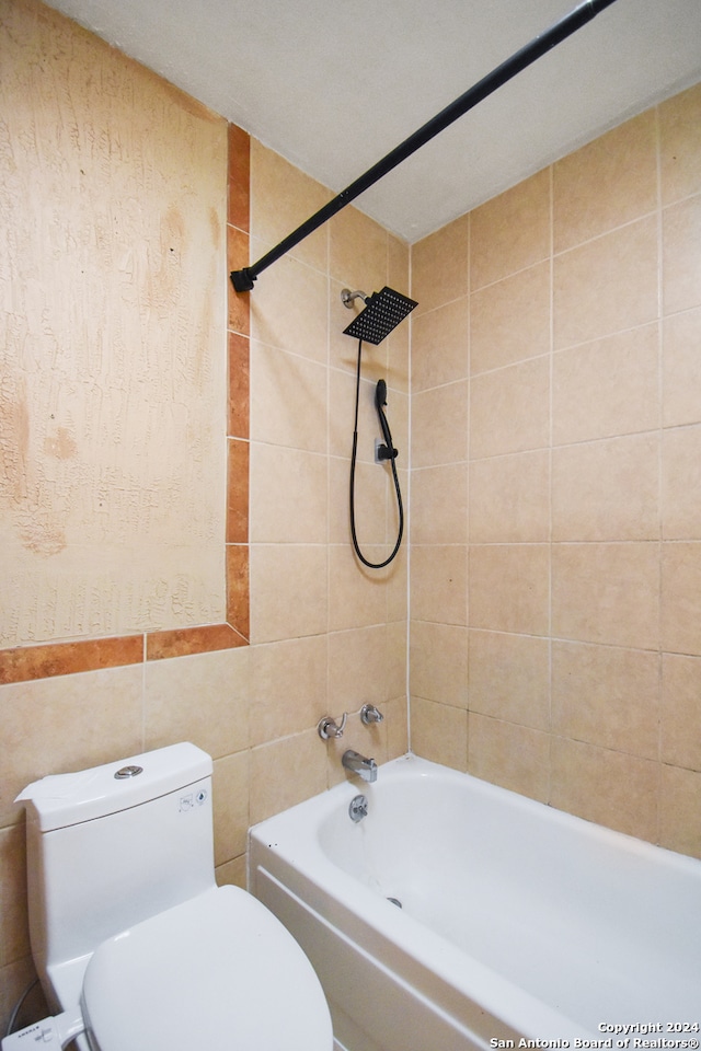 bathroom featuring tile walls, tiled shower / bath combo, and toilet