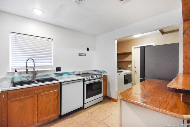 kitchen featuring light tile patterned flooring, refrigerator, dishwasher, stainless steel electric range, and sink