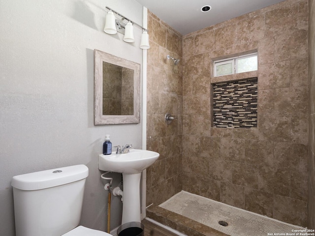 bathroom featuring sink, toilet, and a tile shower