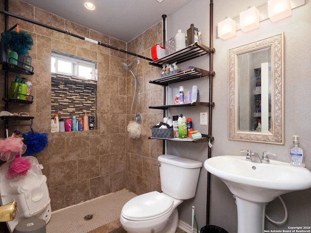 bathroom featuring tiled shower, sink, and toilet