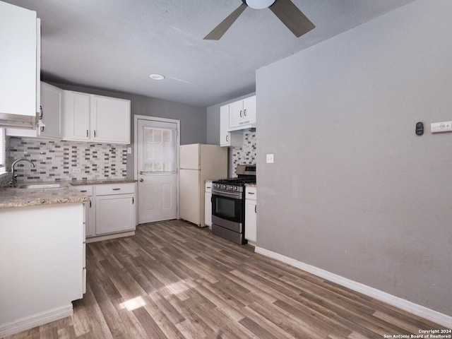 kitchen with stainless steel range with gas stovetop, decorative backsplash, white fridge, sink, and white cabinetry