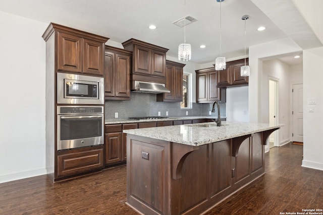 kitchen with dark hardwood / wood-style floors, stainless steel appliances, sink, a center island with sink, and decorative light fixtures