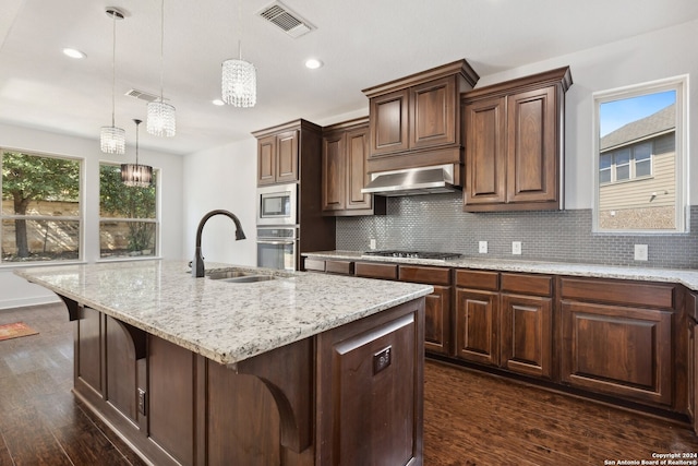 kitchen with a kitchen island with sink, dark wood-type flooring, appliances with stainless steel finishes, plenty of natural light, and range hood