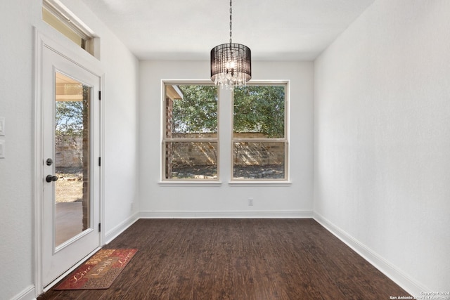 unfurnished dining area with dark wood-type flooring, an inviting chandelier, and a healthy amount of sunlight