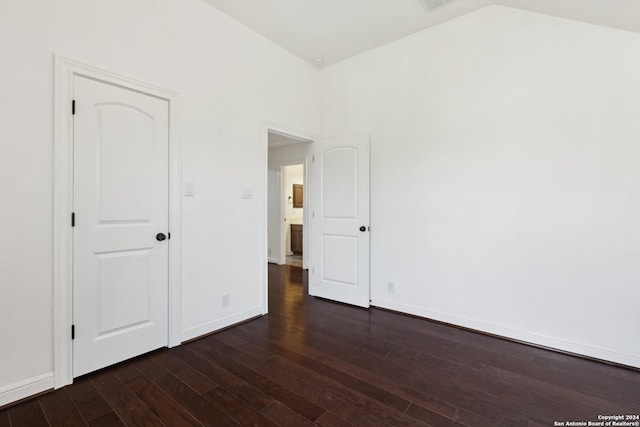 empty room featuring vaulted ceiling and dark wood-type flooring