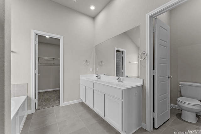 bathroom with tile patterned floors, a tub, vanity, and toilet