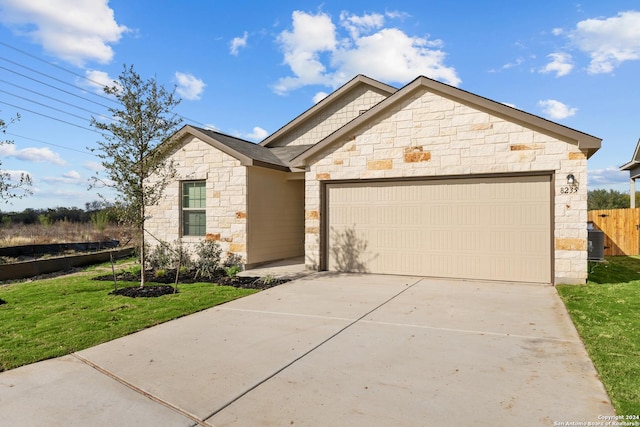 view of front of property with central AC unit, a garage, and a front lawn