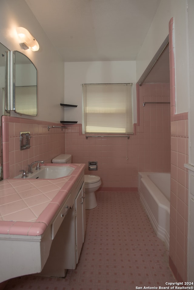 bathroom with tasteful backsplash, tile walls, tile patterned flooring, toilet, and vanity