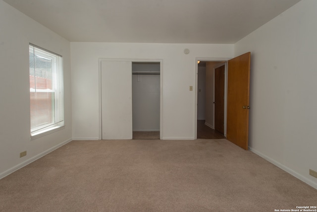 unfurnished bedroom with multiple windows, carpet, and a closet