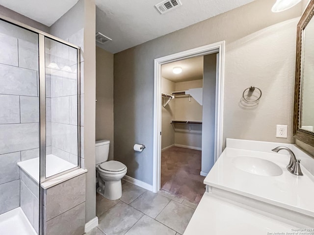 bathroom with tile patterned flooring, vanity, toilet, and walk in shower