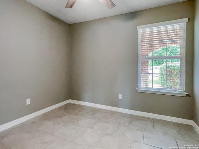 spare room with ceiling fan and light tile patterned floors