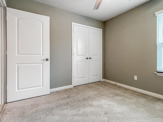 unfurnished bedroom featuring ceiling fan, light colored carpet, and a closet