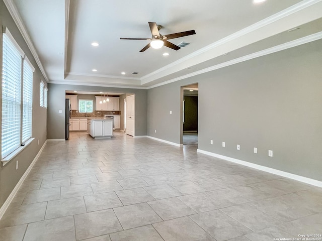 unfurnished living room with light tile patterned flooring, ceiling fan, ornamental molding, and a raised ceiling