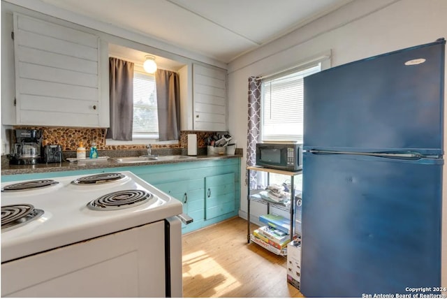 kitchen featuring dark countertops, black appliances, a wealth of natural light, and a sink