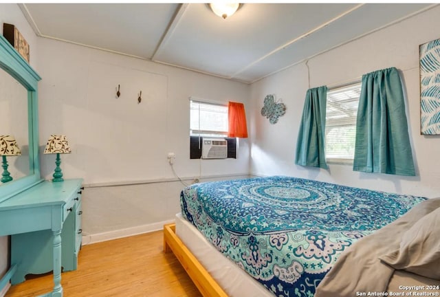 bedroom with light wood-type flooring, cooling unit, and baseboards